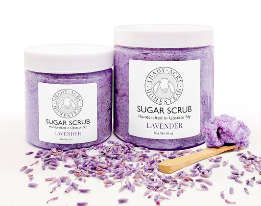 Two jars of lavender sugar scrub with lavender petals and a wooden spoon