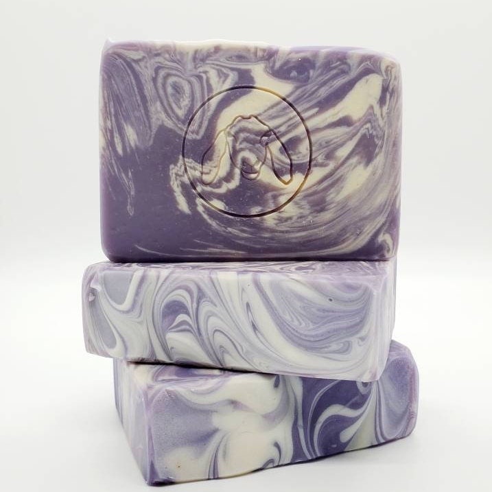 Stack of three handmade marbled soap bars in purple and white.