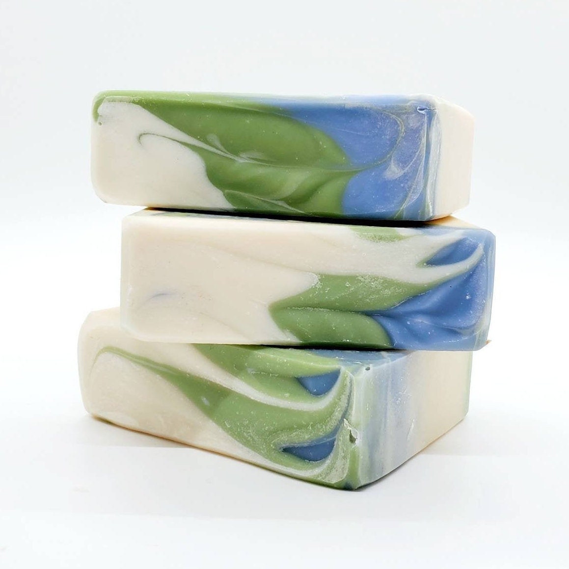 Three stacked bars of soap with swirls of green and blue.